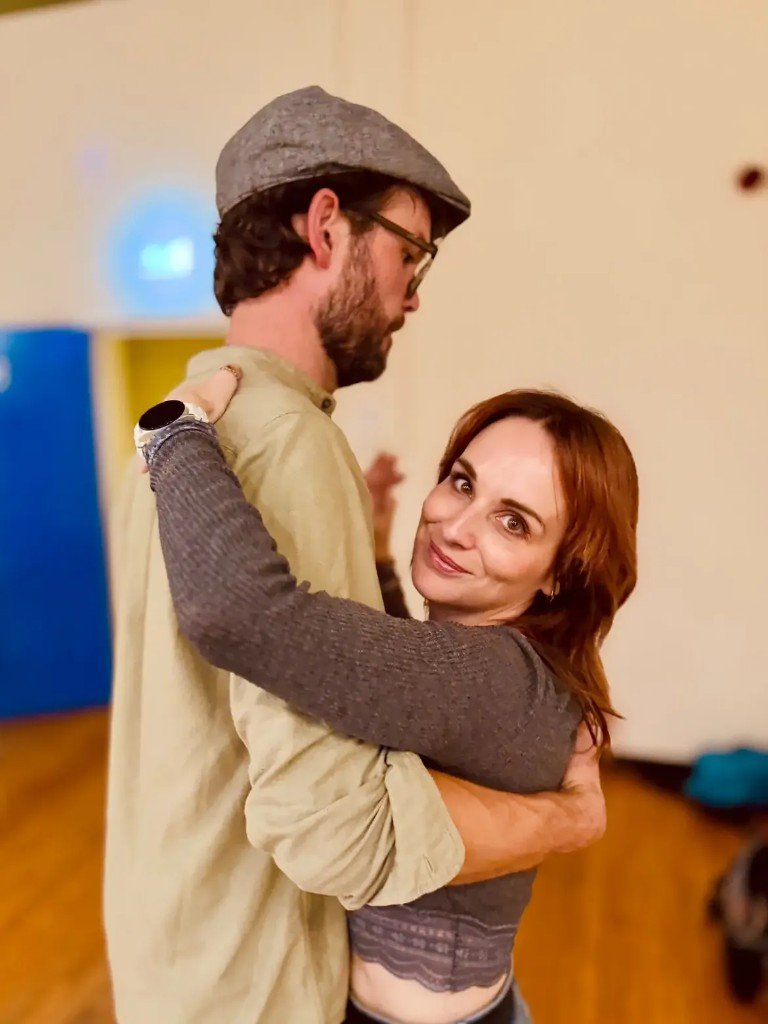 Couple dancing Forró closely, smiling at the camera