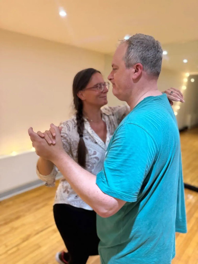 Man and woman partner dancing and smiling in class
